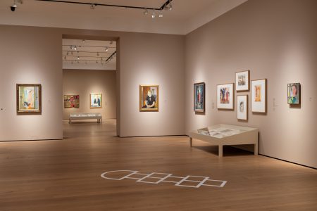 Utstillingsrom med malerier på veggene og et paradis-mønster malt på gulvet, del av Else Hagen-utstillingen på Nasjonalmuseet.
