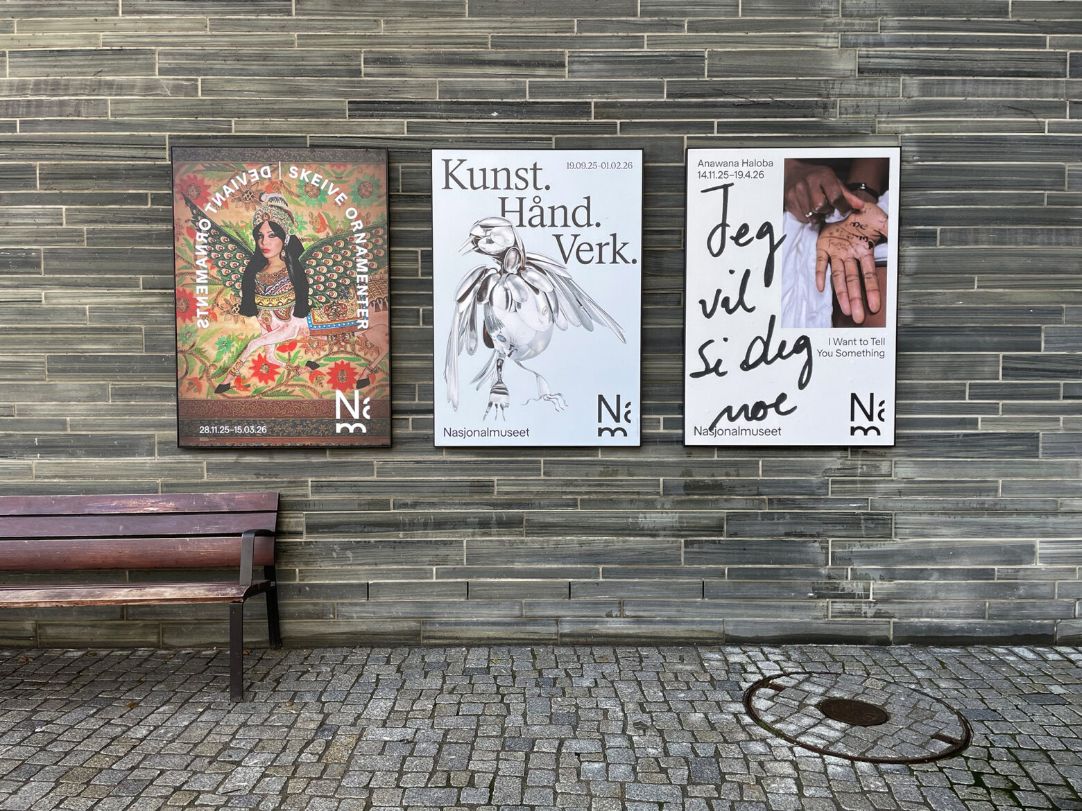 Plakat for utstillingen Deviant Ornaments montert i plakatoppheng på fasaden av Nasjonalmuseet, sammen med plakater for utstillingene Kunst.Hånd.Verk og Jeg vil si deg noe.